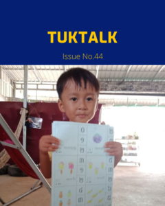 TukTalk Issue No. 44 cover with a smiling young boy holding up a printed Khmer worksheet