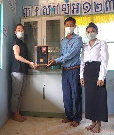 Three people stand beside a new cabinet holding a speaker delivered to the preschool