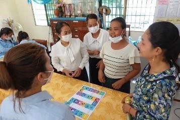 Teachers gather around a colourful printable board game on a table during the first workshop