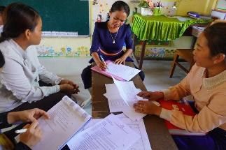 Teachers and assessors go through paper assessment sheets together at a classroom table