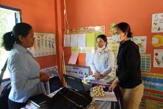 Two women review a classroom assessment in front of a colourful wall of teaching displays