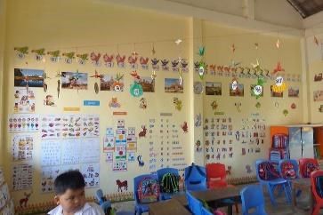 A preschool classroom with pictures, posters and ornaments covering the walls