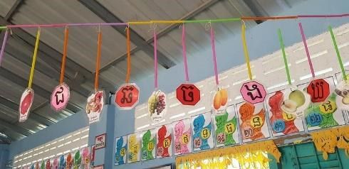 Hand-made ornaments hang on strings along the ceiling of a preschool classroom