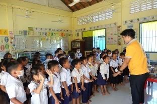 A project staff member in a yellow shirt speaks to preschool children standing in lines in their classroom