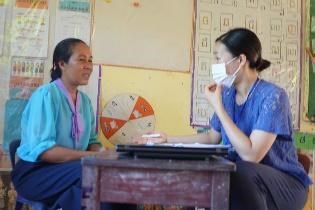 A preschool teacher and a project staff member talk at a small desk during a follow-up visit