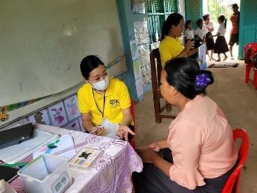 A staff member in a yellow shirt sits with a teacher at a small table during a school visit