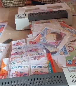 A laminating machine and a pile of laminated picture cards on a table