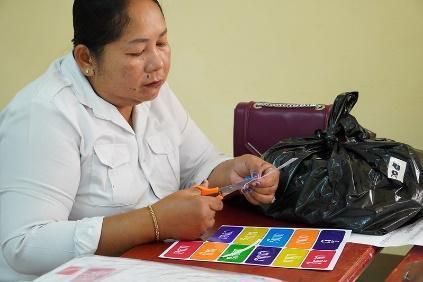 A woman cuts out colourful cards with scissors at a table during the classroom decoration session