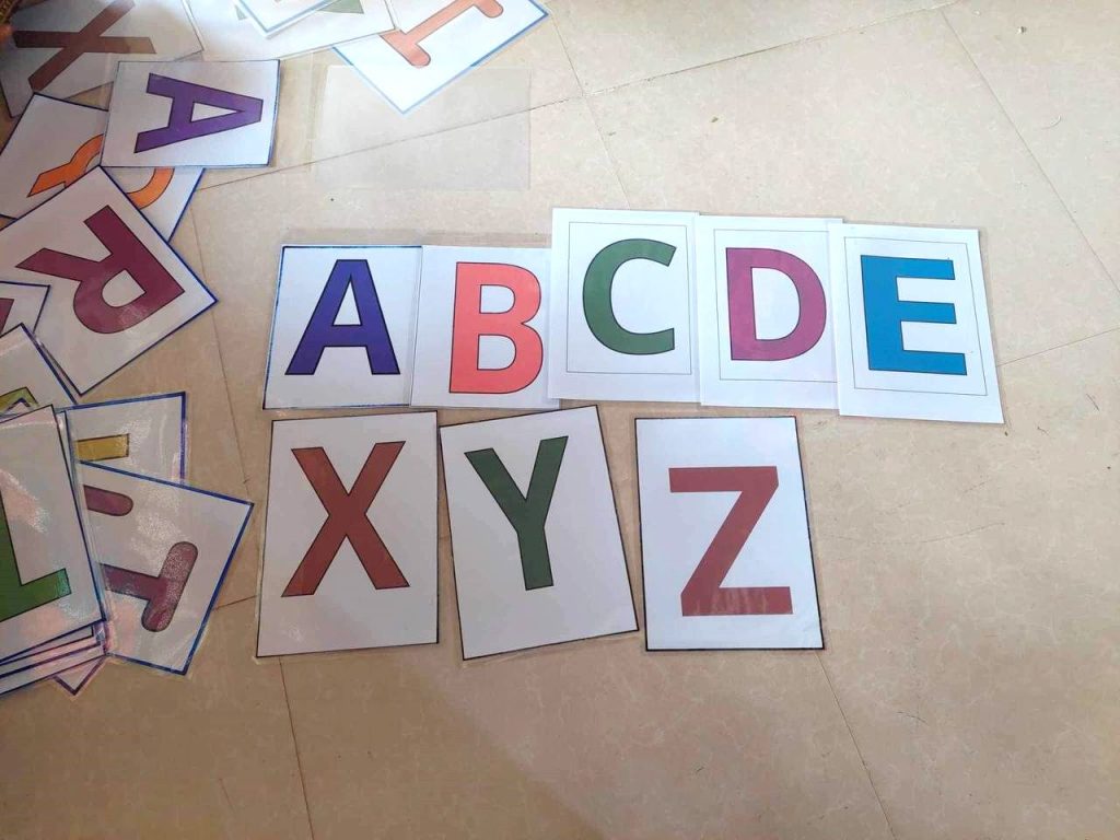 Colourful printed letter cards of the English alphabet laid out on a floor