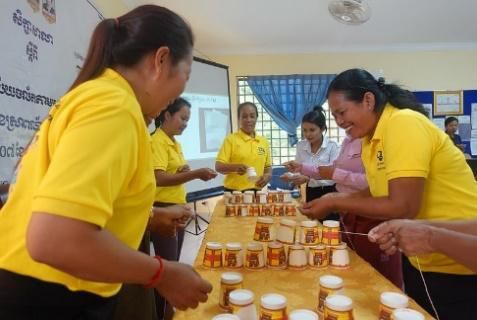 Teachers in yellow shirts arrange small jars on a table during an activity at the workshop