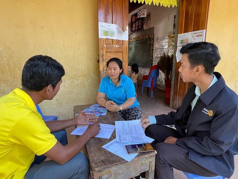 Two project staff talk with a preschool teacher at a table during a baseline survey interview