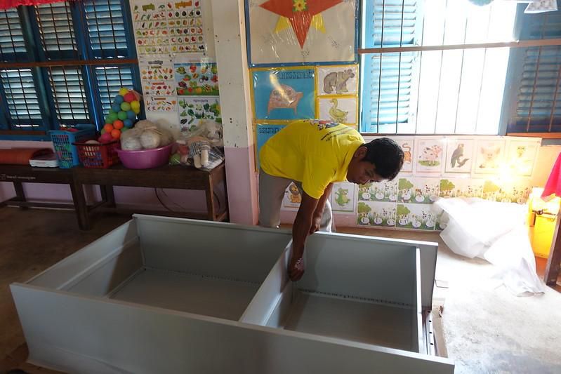 A project staff member assembles a lockable metal cabinet in a preschool classroom