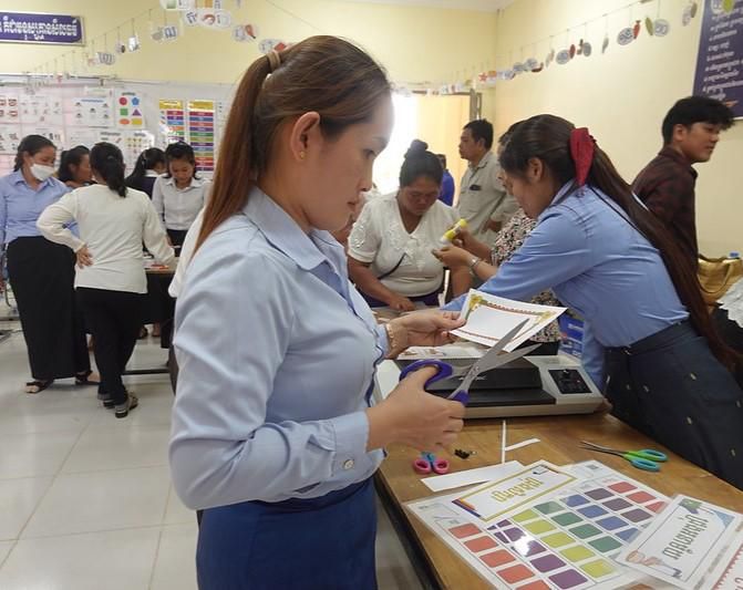 Teachers cut and prepare classroom decorative teaching tools at a worktable during the pre-project workshop