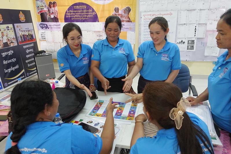 Teachers gather around a board game and try out the resource package during the first workshop