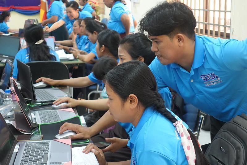 Teachers practise computer basics on laptops while an instructor guides them during the first workshop