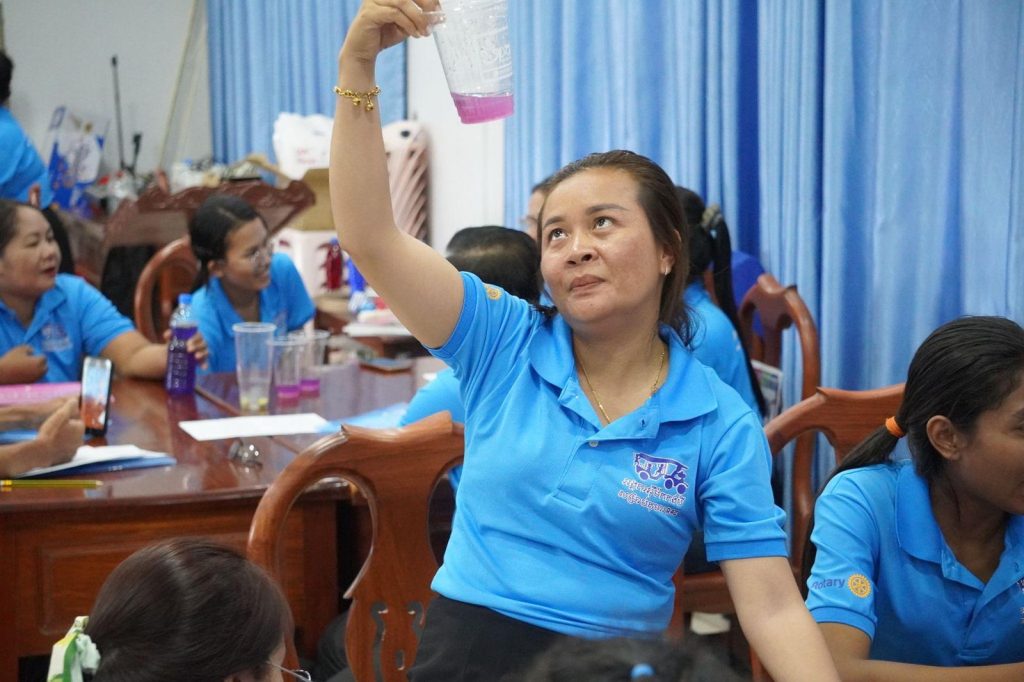 A teacher raises a cup toward the light during the color-change experiment as others watch