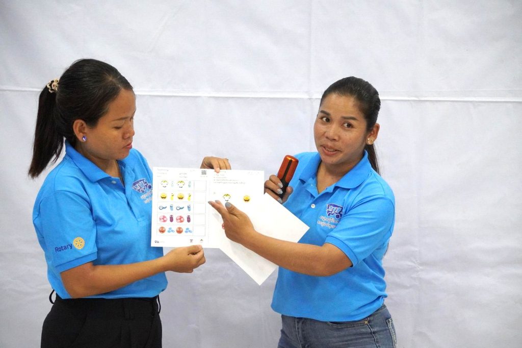 Two teachers hold up a worksheet together to present it to the group