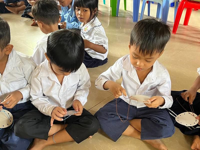 Two boys sit side by side on the classroom floor, absorbed in a hands-on activity game