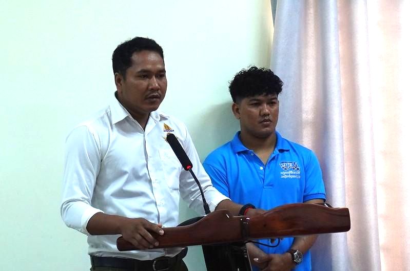 A presenter speaks into a microphone beside a colleague during the annual meeting