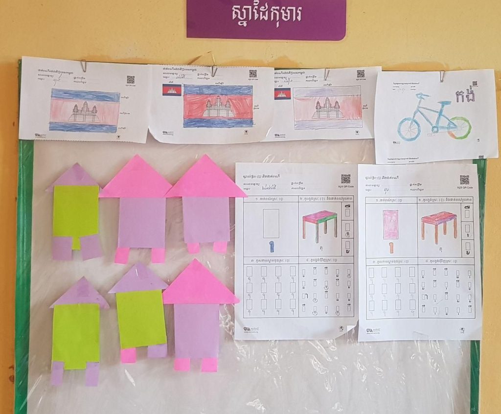 Handmade paper houses and worksheets pinned to a classroom display board