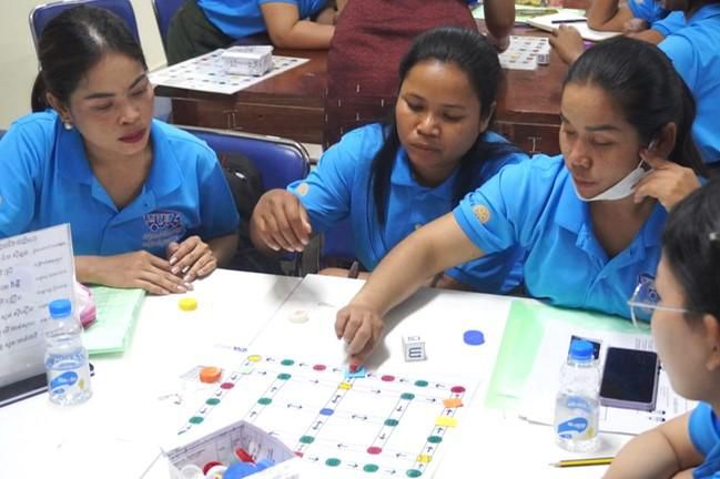 Teachers play a colourful board game with counters around a table at the workshop