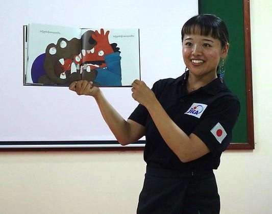 A JICA volunteer shows an open picture book while telling a story at the workshop