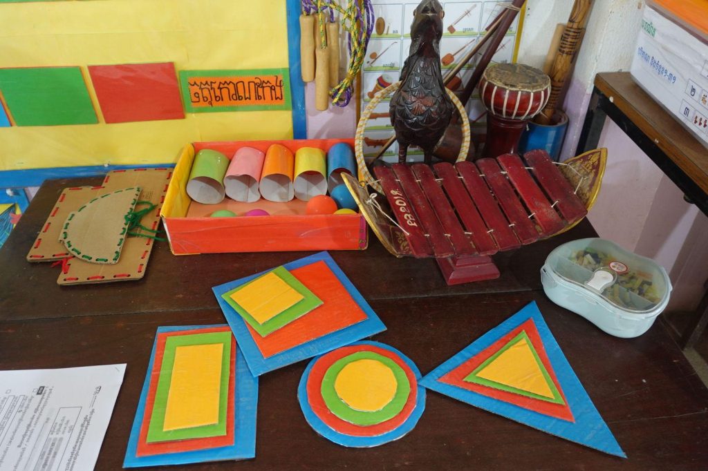 Colorful handmade shapes and wooden instruments displayed on a classroom table