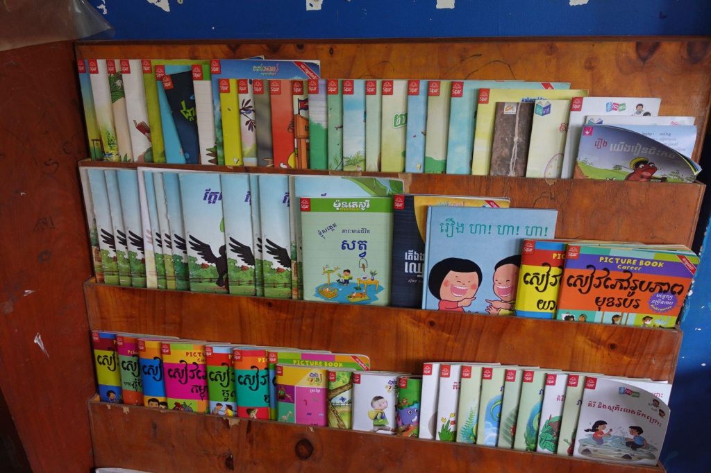 Storybooks arranged on a wooden shelf in a classroom reading corner