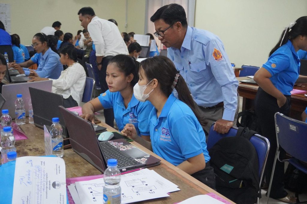 Teachers in blue shirts work at laptops in the computer worksheet session of the sixth workshop