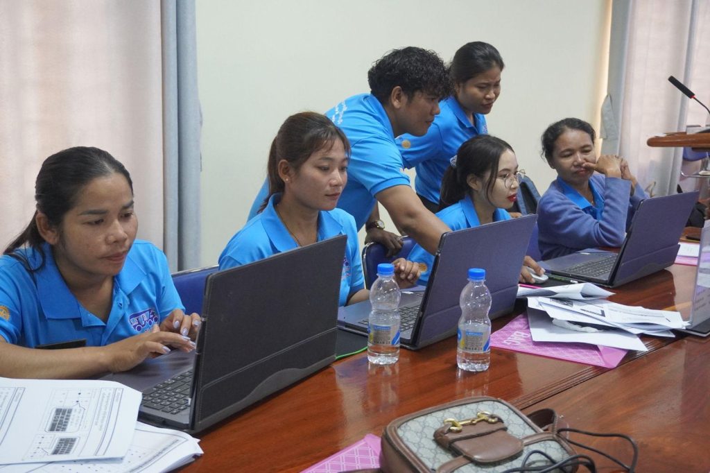 Teachers type on laptops side by side at a long table during the Word worksheet session