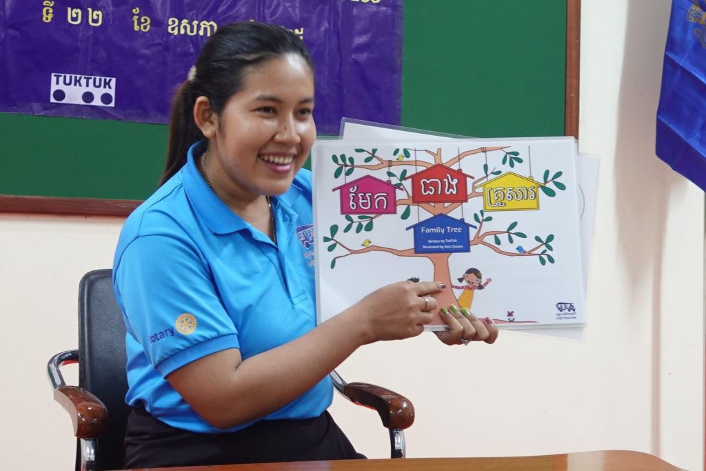 A teacher smiles and holds up the Family Tree picture book at the workshop