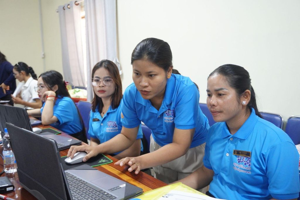 Three teachers work together at a laptop during the worksheet-making session