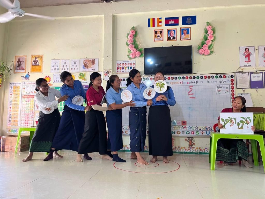 Six teachers stand in a line holding paper plates to act out a story for their peers