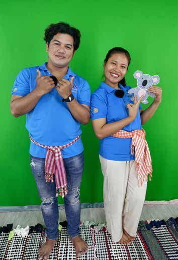 Two Sala Rean Sabey presenters in blue shirts pose in front of a green screen holding a toy koala.