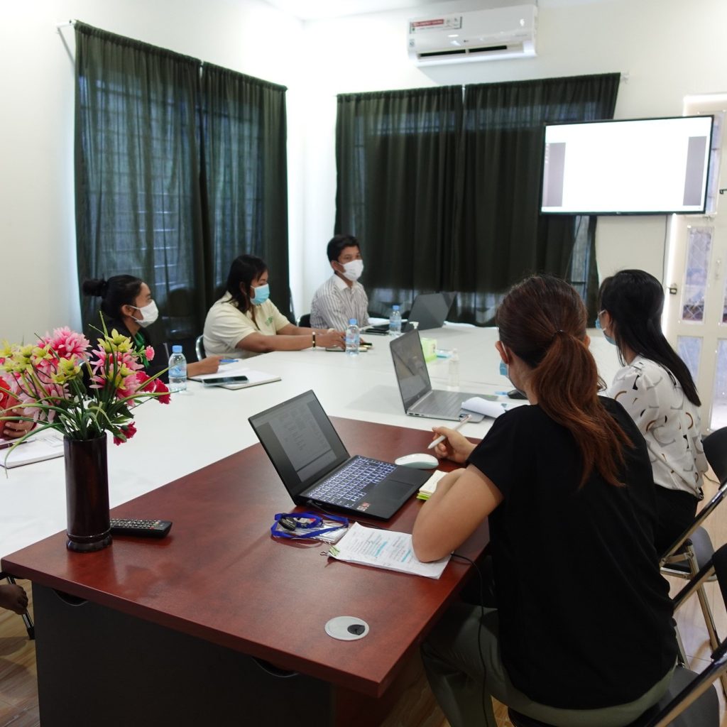 TukTuk staff sit around a meeting table with laptops in the office