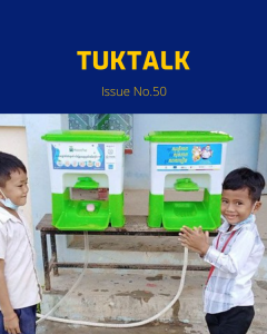 Two boys stand beside green hand wash stands at a school