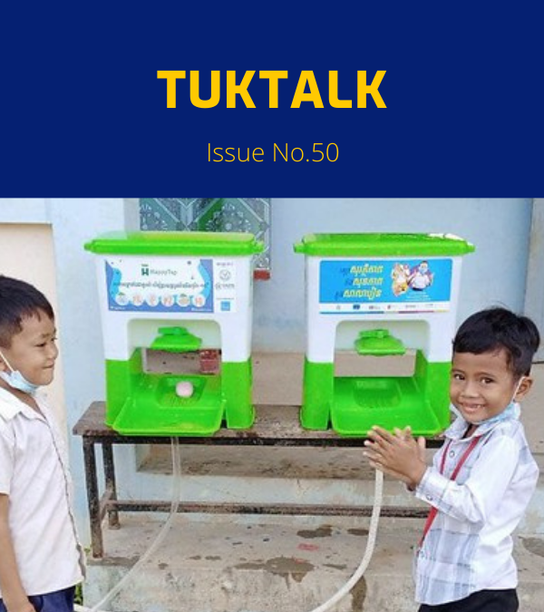 Two boys stand beside green hand wash stands at a school