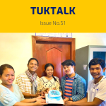 Five TukTuk staff hold a birthday cake together in the office