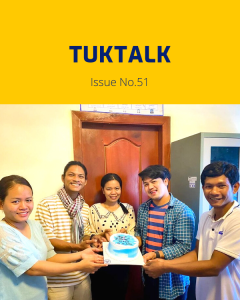 Five TukTuk staff hold a birthday cake together in the office