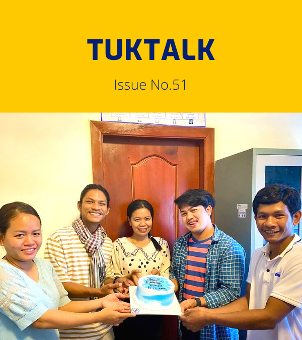 Five TukTuk staff hold a birthday cake together in the office