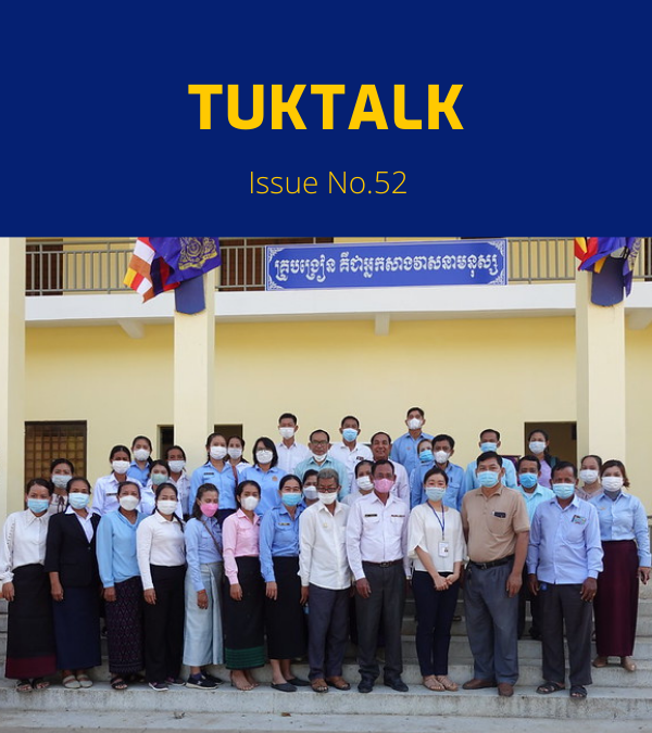 TukTuk staff, teachers and education officials pose in front of a school building