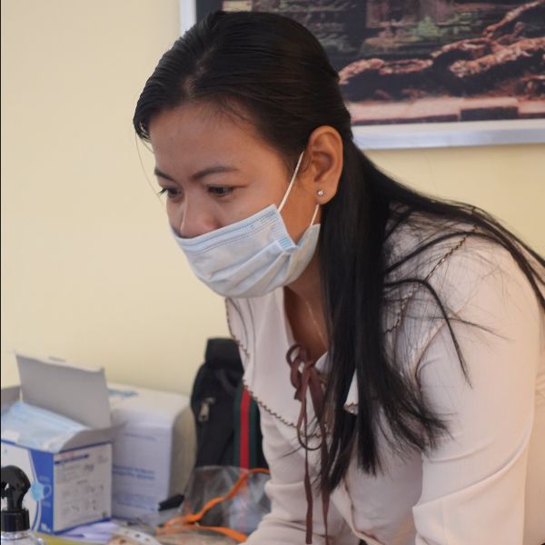 A woman in a face mask looks down at her work at a desk