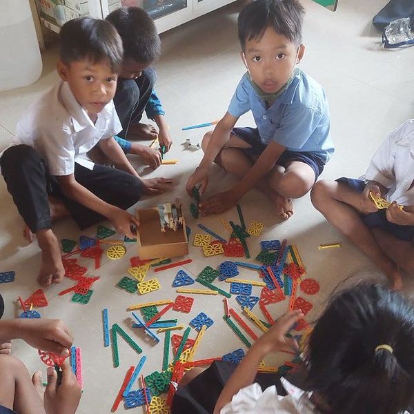 Children sit on the floor playing with colourful building sticks and connectors