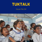 Smiling kindergarten girls in school uniform crowd together and look up