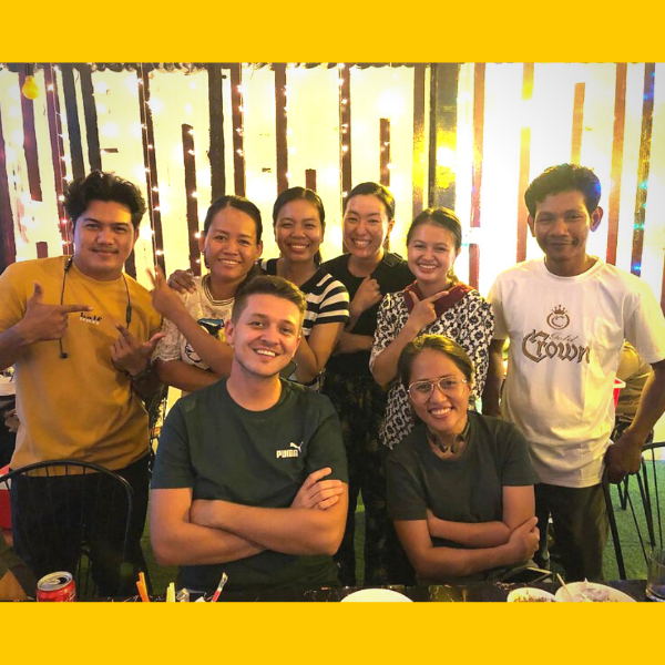 TukTuk staff and visiting volunteers pose smiling around a restaurant table in the evening