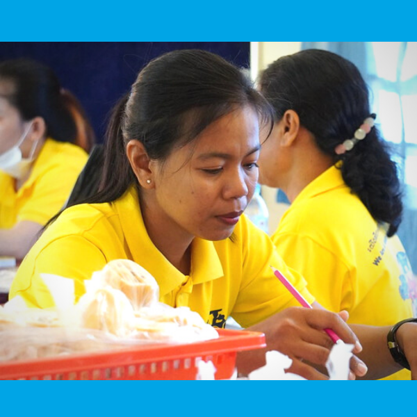Two teachers in yellow shirts work at a table during the workshop