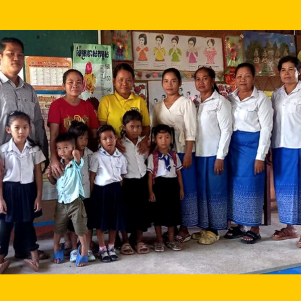 Teachers and kindergarten children pose together in a classroom