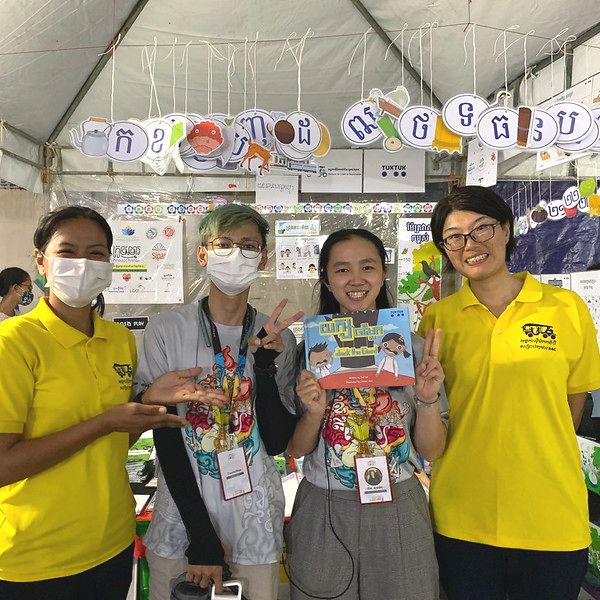 TukTuk staff and young visitors pose with the picture book at the colourful book fair booth