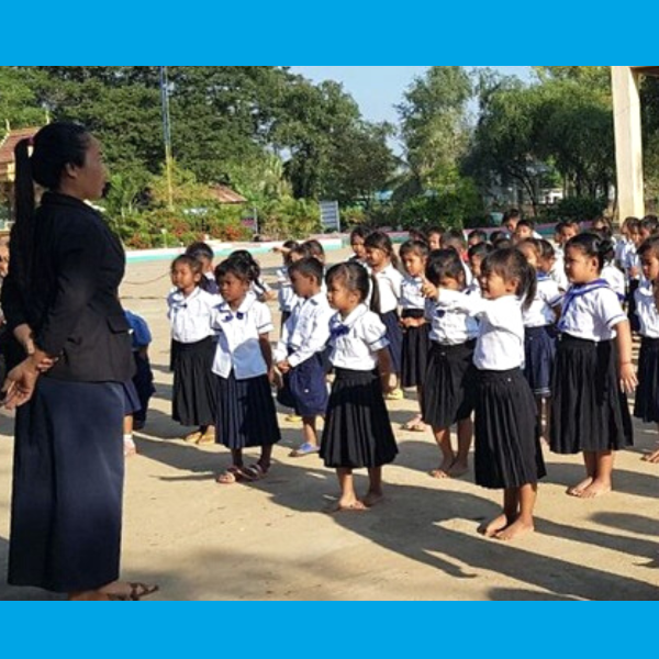 Kindergarten children in school uniform line up in the school yard with their teacher