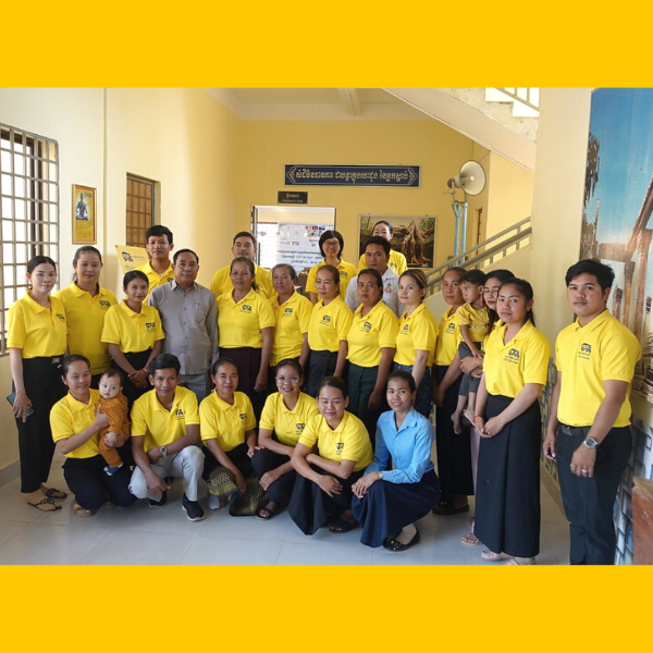 TukTuk staff in yellow shirts pose together for a group photo in a hallway